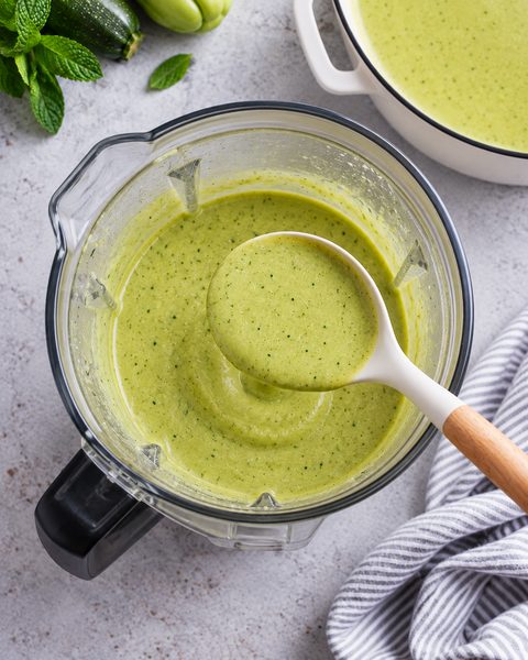 Crema verde tersa en el vaso de la licuadora, con un cucharón que la levanta
